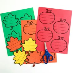 paper cut out to look like apples and leaves with scissors next to them on a white surface