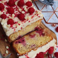 two slices of cake with raspberries and white frosting on a cutting board