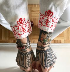 a person with tattoos on their feet wearing white pants and red accents, holding onto her leg