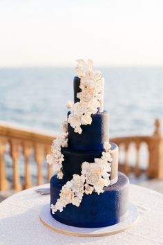 a blue wedding cake with white flowers on top