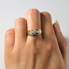 a woman's hand with a gold and white diamond ring on her left hand