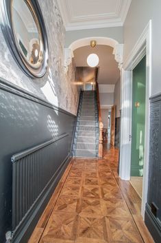 an empty hallway with stairs leading up to the second floor and a mirror on the wall