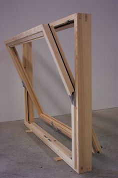 an unfinished window frame sitting on top of a cement floor in front of a white wall