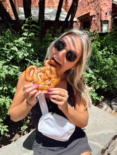 a woman in sunglasses is eating a pretzel