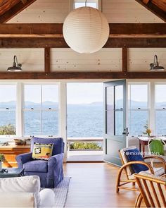 a living room filled with furniture next to a window covered in lots of windows overlooking the ocean