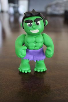 a green toy is standing on a brown table and it looks like he's angry