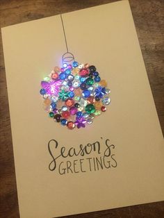 a christmas ornament hanging from a card with the words season's greetings