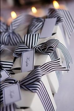 several wrapped gift boxes with black and white ribbons on them, sitting next to candles