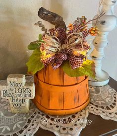 a wooden basket filled with leaves and flowers on top of a doily covered table