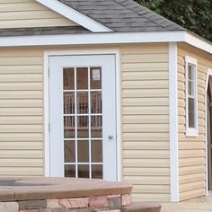 a dog is sitting on a bench in front of a small house