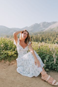 This exclusive Wisteria Lane dress is a playful and stylish addition to any wardrobe. The cream base is embellished with a delicate light blue floral print and embroidered details. The midi length and flutter sleeves add a touch of whimsy, while the decorative buttons, ruching, and ruffled tiers provide a flirty and feminine touch. Perfect for a day out in the sun or a special occasion. Details Cream dress with light blue floral print Cream embroidered details Nonfunctional buttons down front of Nursing Friendly Tops, Wisteria Lane, Free People Sandals, Nursing Friendly Dress, Plus Jumpsuit, Cream Base, Exclusive Dress, Embroidered Details, Blue Floral Print