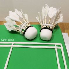 two cake decorations made to look like badminton rackets and shuttles on a green surface