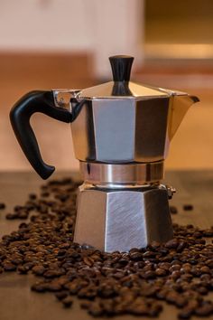 a coffee pot sitting on top of a pile of coffee beans