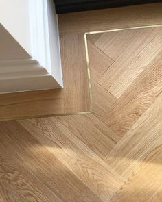 the corner of a room with wood flooring and white trim on the door frame