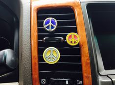 three peace signs are on the dashboard of a car with wood trim and leather interior