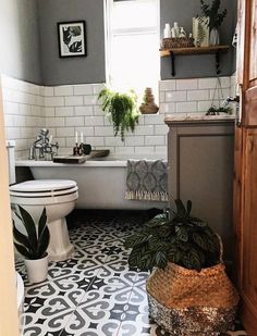 a bathroom with black and white floor tiles, potted plants and a bathtub