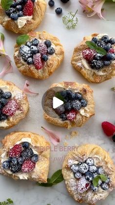 several pastries with berries and powdered sugar on them sitting on a white surface