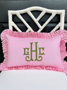 the monogrammed pillow has been made with pink and white ticking fabric, which is accented with green letters