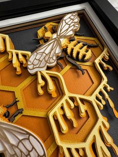 a close up of a framed artwork with bees and honey combs on it's sides