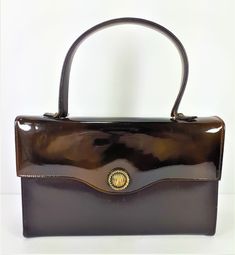 "Chocolate Brown Faux Patent Leather Purse, Handbag, Small Handbag, Goldtone Hardware, Snap Button Closure, Vintage 1960s Vegan leather handbag purse the top flap is faux patent leather and the rest of the bag is a textured faux leather. Snap Button Closure One inside pocket and one zipper pocket.  Black and gold interior. Measures approximately: 9\" wide by 5.75\" tall by 2\" deep (at widest point) with an 4.5\" strap drop. The purse has some wear on the goldtone hardware, there are some scuffs Black And Gold Interior, Vintage Easter Postcards, Vintage Kelly, Small Handbag, Vintage Branding, Small Handbags, Vintage Handbags, Vintage Bags, Vintage 1960s