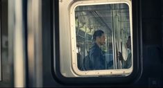 a man is looking out the window of a subway car as it's inside