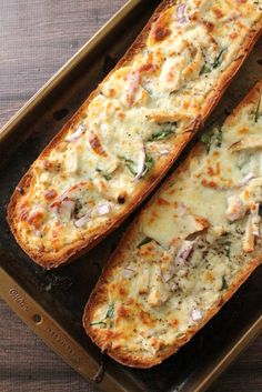 two pieces of bread sitting on top of a baking pan filled with cheese and vegetables