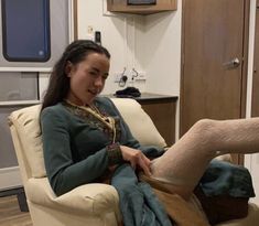 a woman sitting in a chair with her feet on the foot rest and wearing socks