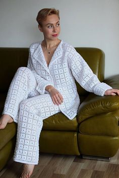 a woman sitting on top of a green couch wearing white pajamas and heels with her legs crossed