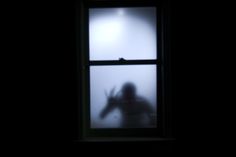 the silhouette of a person standing in front of a window