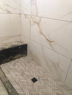 a bathroom with marble walls and flooring next to a black box on the ground