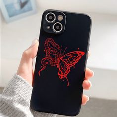 a person holding up a phone case with a red butterfly on it