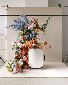 a white suitcase sitting on top of a table next to flowers