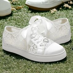 two white shoes with bows on them sitting in the grass next to some other shoes