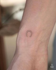 a woman's wrist with a small horseshoe tattoo on the left side of her arm