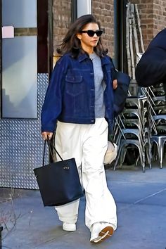 a woman walking down the street carrying two bags