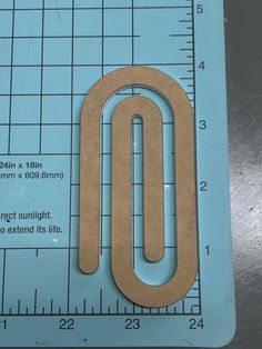 a piece of cardboard with a paperclip on it next to a measuring ruler