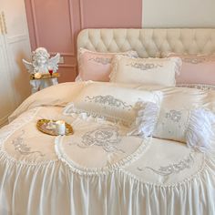 a white bed topped with lots of pillows next to a night stand filled with candles