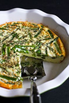 a quiche with cheese and asparagus in a white dish on a black table