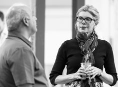 a black and white photo of a woman holding a glass in her hands while standing next to an older man