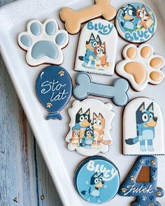 some decorated cookies are on a white platter with blue and orange designs, including dogs