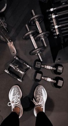 a person standing in front of some dumbs and exercise equipment with their feet on the ground