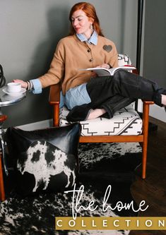 a woman sitting in a chair with a cow print pillow on the floor next to her