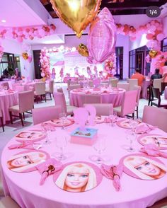 a table with pink and gold decorations in a banquet hall filled with tables, chairs, and balloons