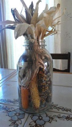 a glass jar filled with corn on the cob sitting on top of a table