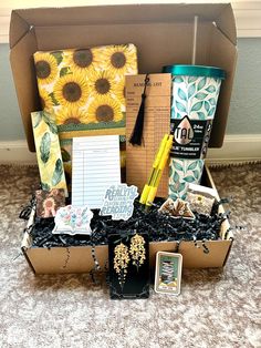 an open cardboard box filled with assorted items on carpeted floor next to wall