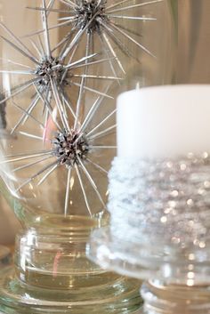 two glass vases sitting on top of a table next to each other with candles in them