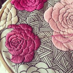 a close up of a embroidery on a piece of cloth with pink and white flowers