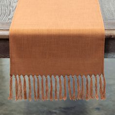 an orange table runner with tassels on it