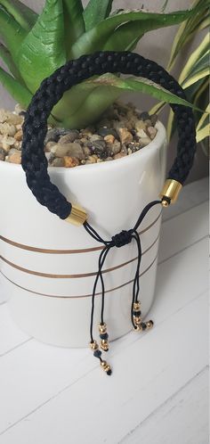 a potted plant sitting on top of a white table next to a black cord bracelet