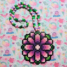 a cross - stitch necklace with beads on it and a beaded flower charm hanging from the front